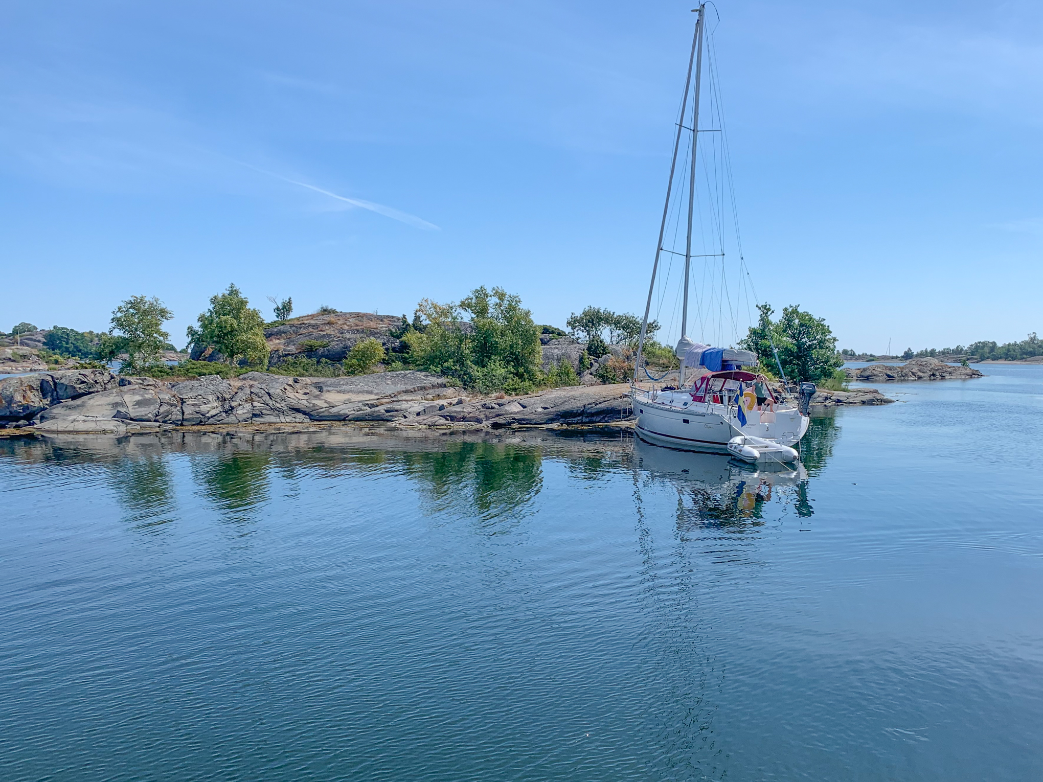 En segelbåt förtöjd i en lugn naturhamn i skärgården